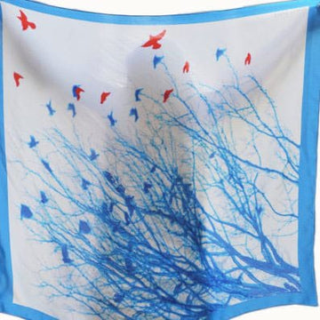 Colorful Bombaybirds Theflighttospring! scarf with floral and abstract patterns, lightweight and soft fabric, draped on a plain background.