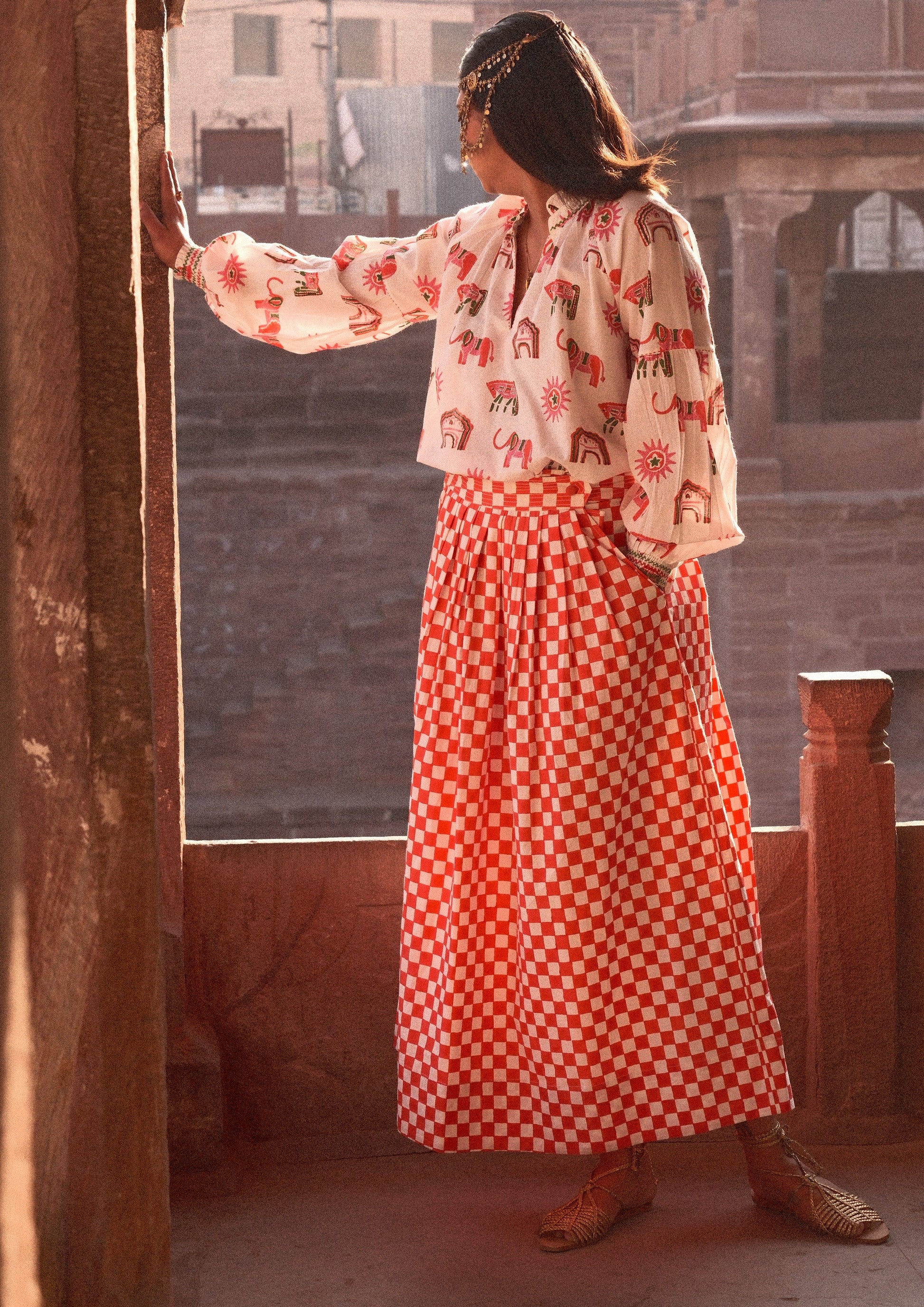 Red check Bawari skirt from The Raw India, featuring traditional patterns and flowy fabric, styled for casual or festive wear.