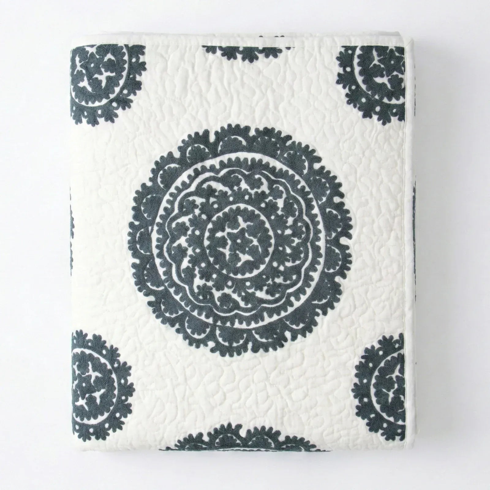 Grey Suzani quilt by Bombaybirds, stylish living room decor featuring intricate textile patterns on soft fabric.