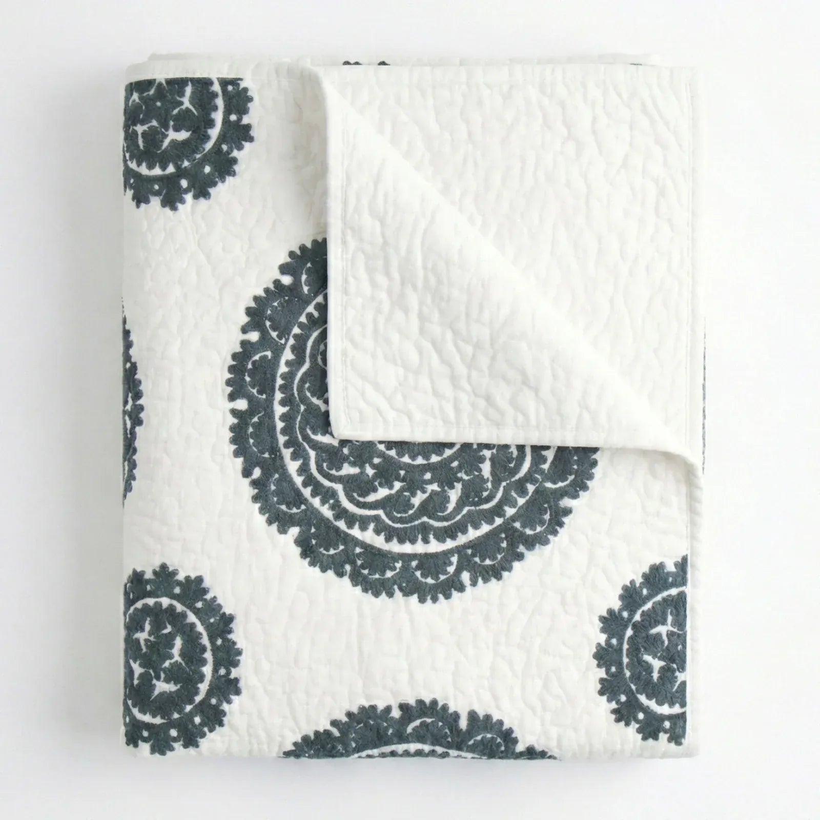 Grey Suzani quilt for living spaces by Bombaybirds, featuring intricate traditional patterns and soft textile texture.
