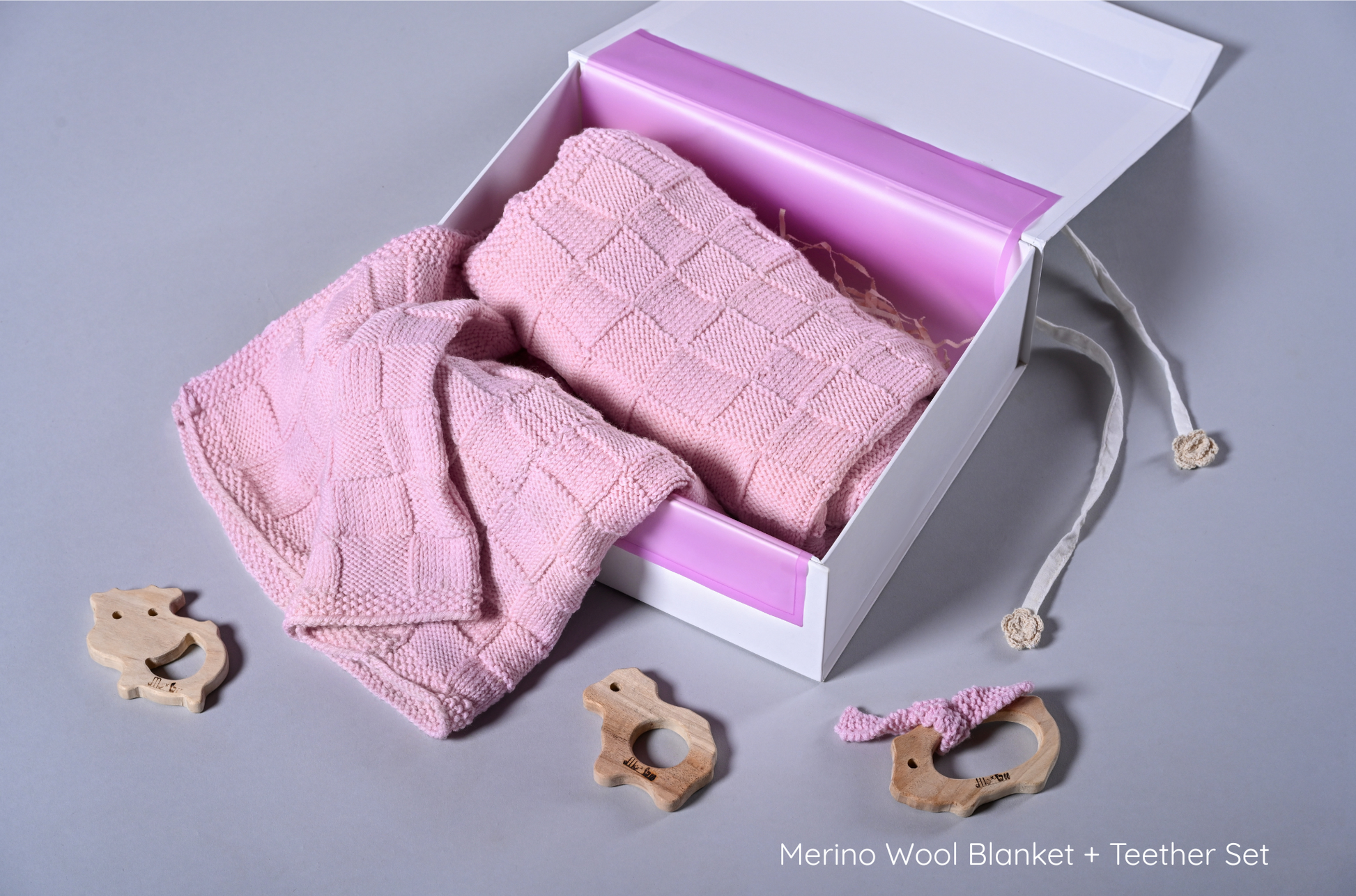 Pink Merino wool blanket from Masaya Home draped over a cozy armchair, showcasing soft, high-quality wool texture.