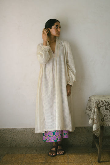 Deeta Noor dress displayed on a hanger, showcasing its elegant design and fabric details in natural lighting.