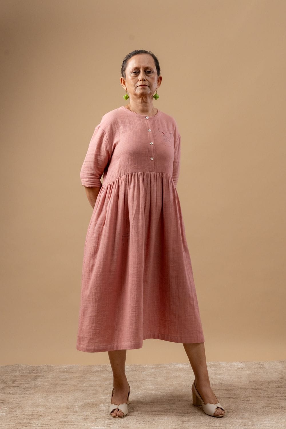 Doodlage Kara rose dress, stylish floral dress with ruffled details, displayed on a hanger with a soft pink background.