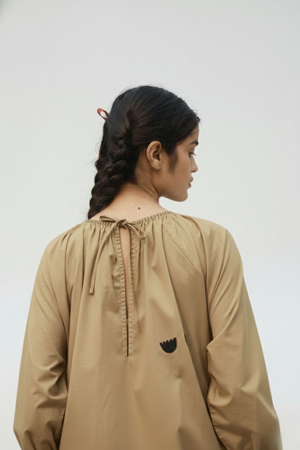 Astrid beige Doodlage dress displayed on a hanger, showcasing its soft fabric and simple, elegant design.