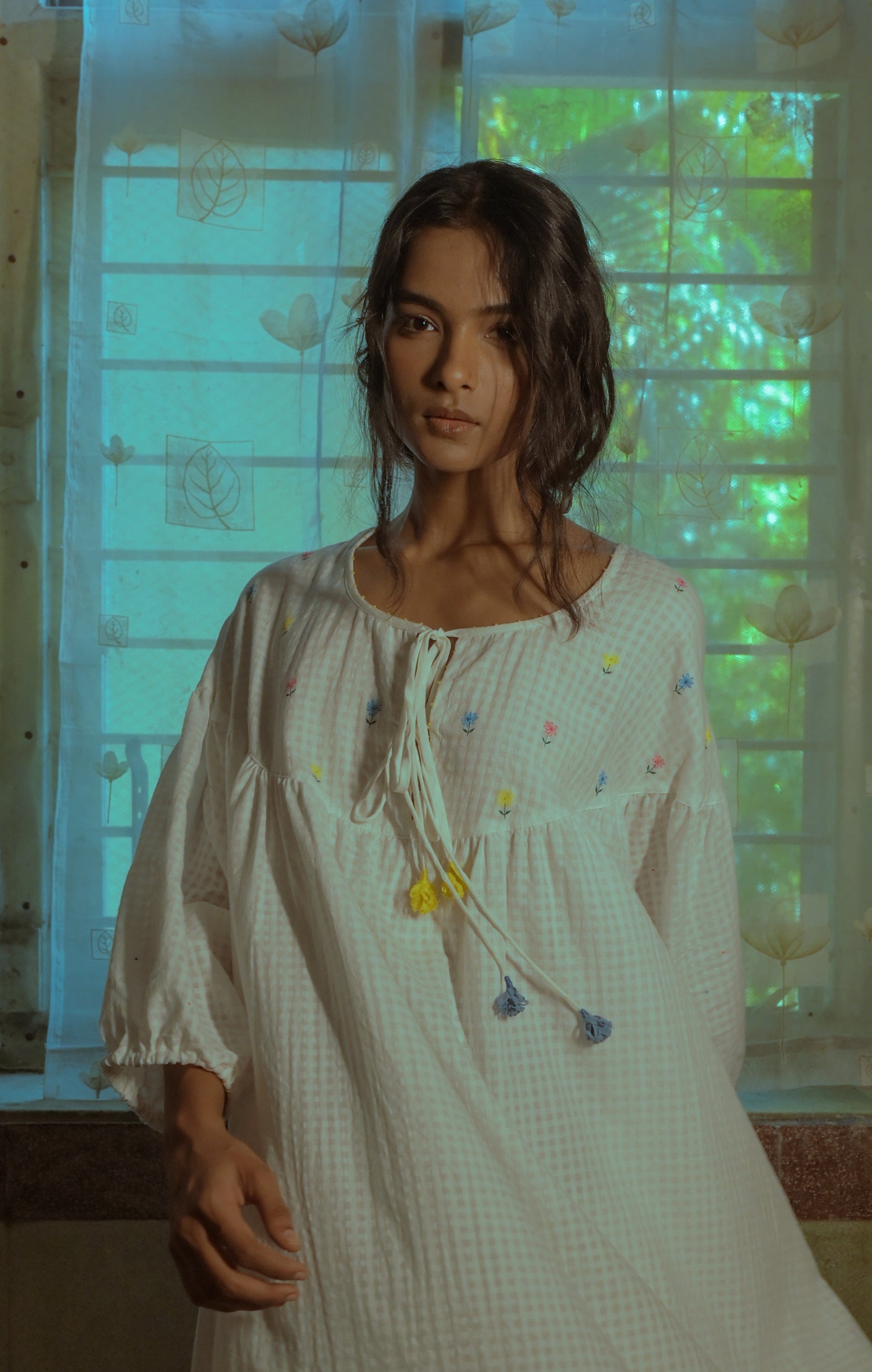 Deeta Flora oversized white dress hanging on a display, showcasing a flowing, elegant design with floral patterns and lightweight fabric.