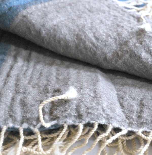Light sky blue Bombaybirds Light Skyz throw blanket draped over a cozy living room sofa, highlighting soft fabric and relaxed style.
