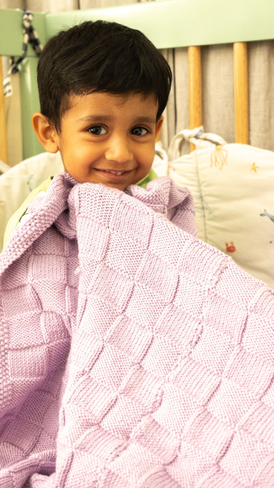 Pink Merino wool blanket by Masaya Home draped over a bed, showcasing its soft texture and cozy appearance.