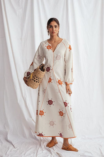 JODI Thandai peasant dress with flowy fabric and intricate embroidery, displayed on a model in a relaxed outdoor setting.