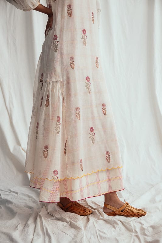JODI Kulfi peasant dress with floral print, flowing fabric, and bohemian style, shown on a model with natural setting background.