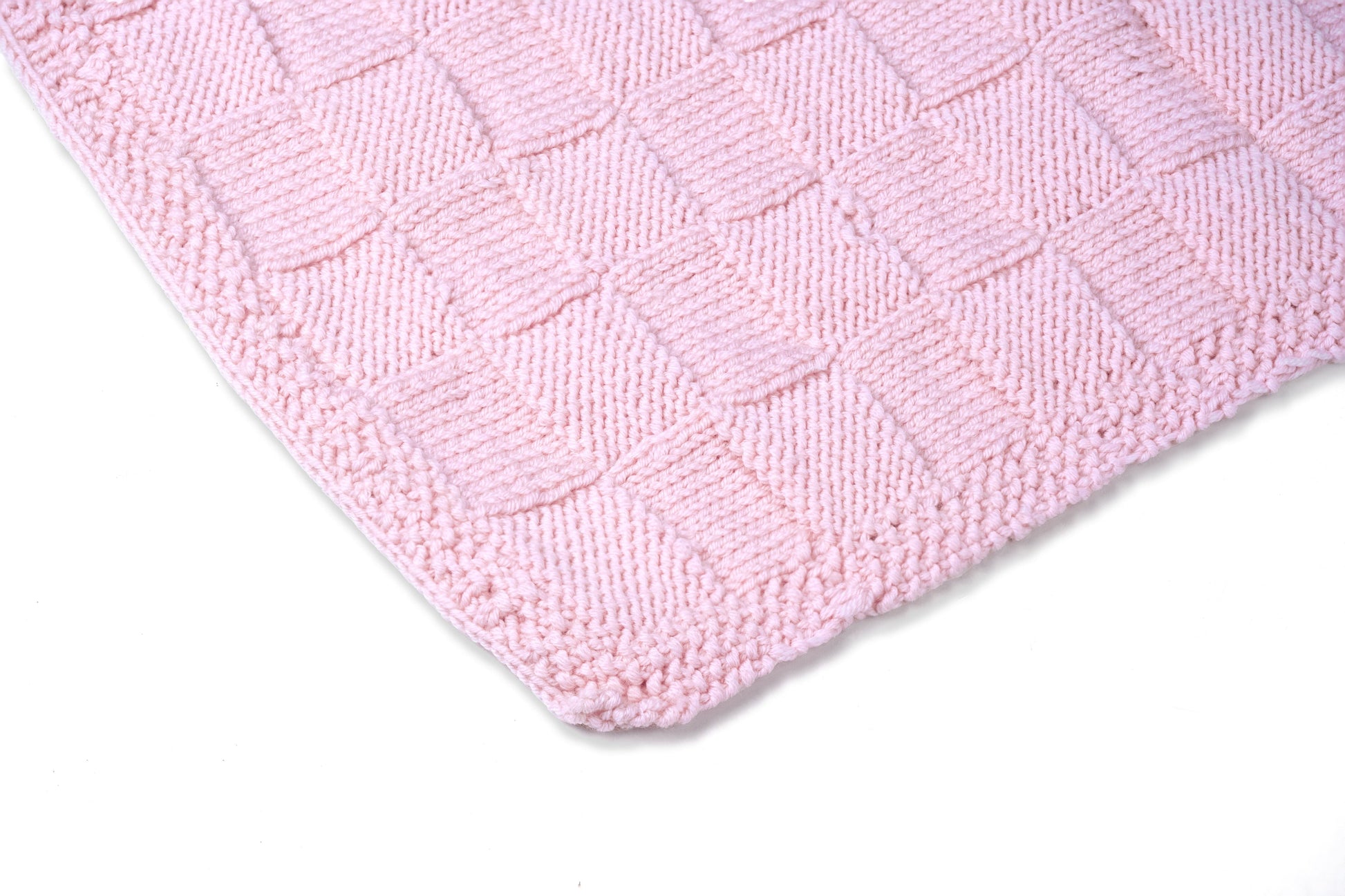 Pink Merino wool blanket by Masaya Home, soft and cozy with a textured knit pattern, draped over a sofa.