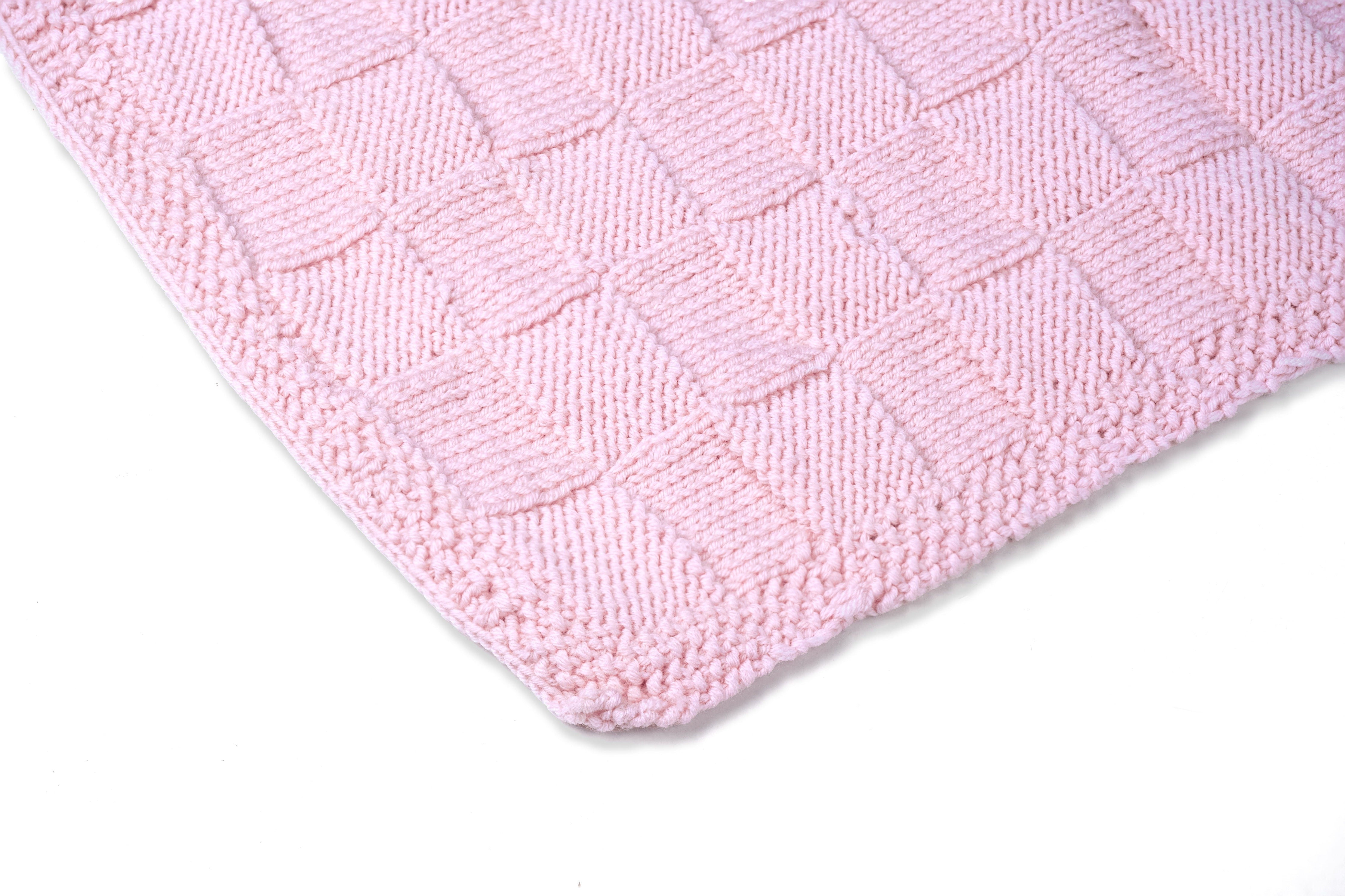 Pink Merino wool blanket by Masaya Home, soft and cozy with a textured knit pattern, draped over a sofa.