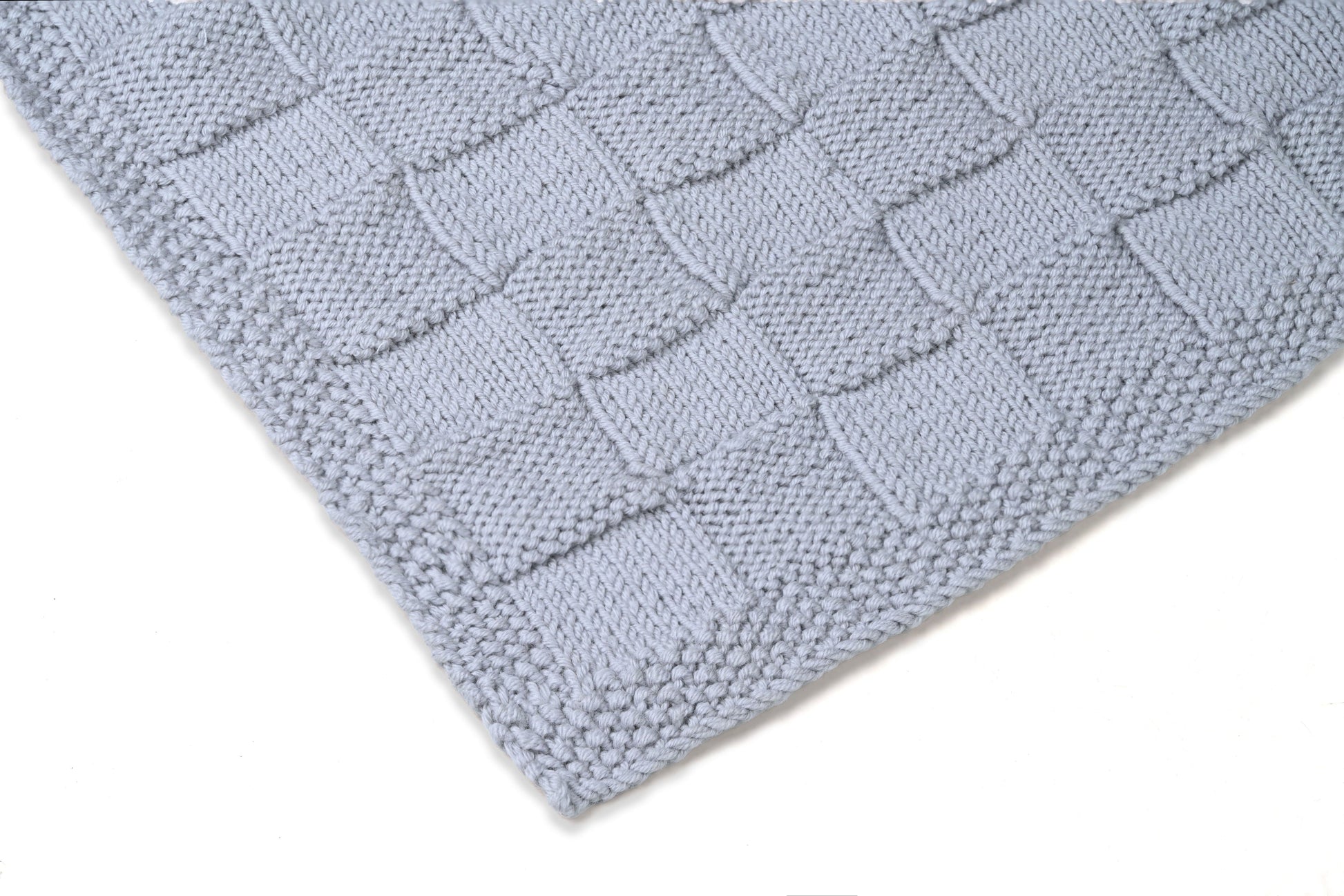 Grey Merino wool blanket by Masaya Home, soft and cozy with a textured knit pattern, draped over a sofa.