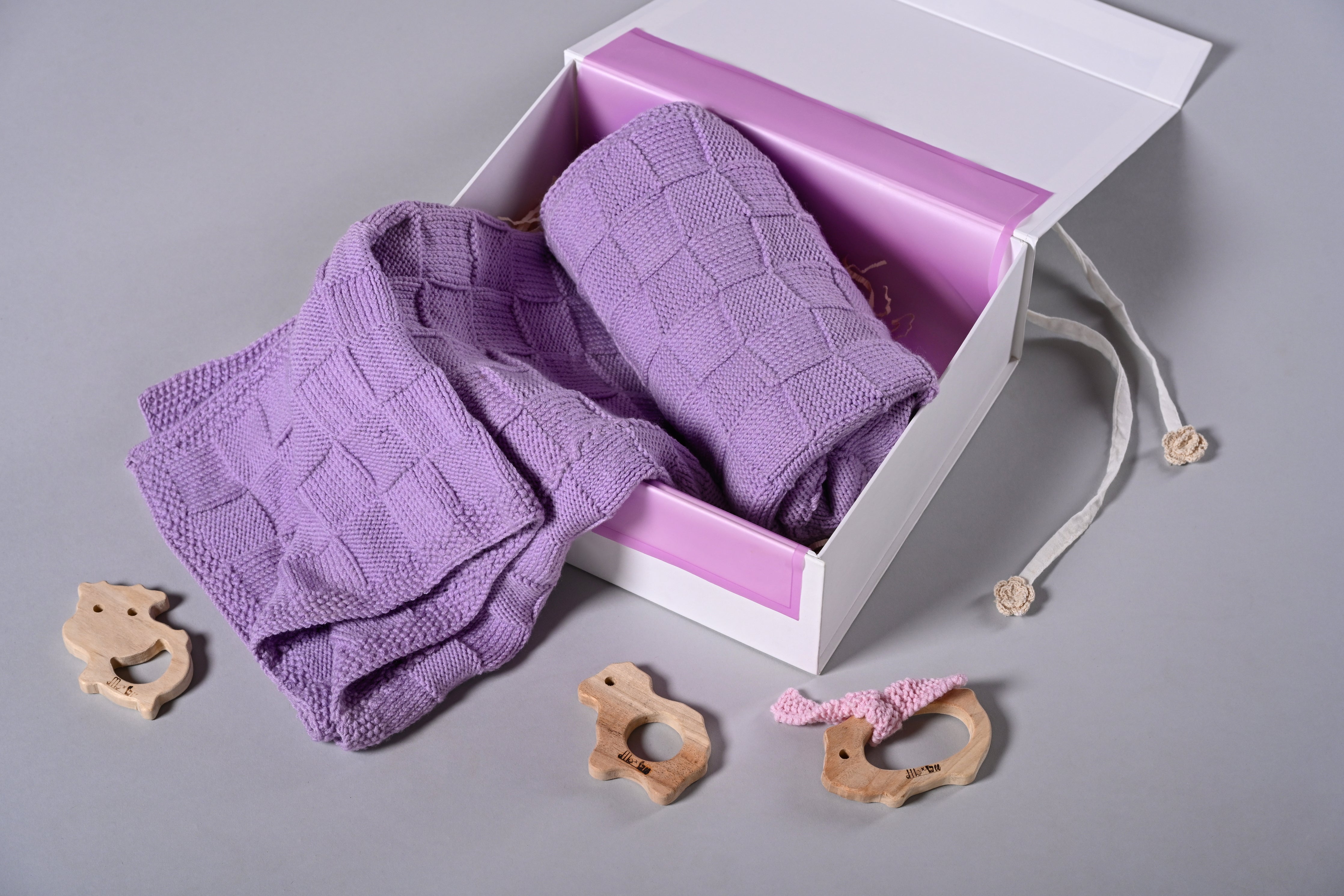 Purple Merino wool blanket from Masaya Home, soft and cozy with a plush texture and woven pattern, draped over a bed or sofa.