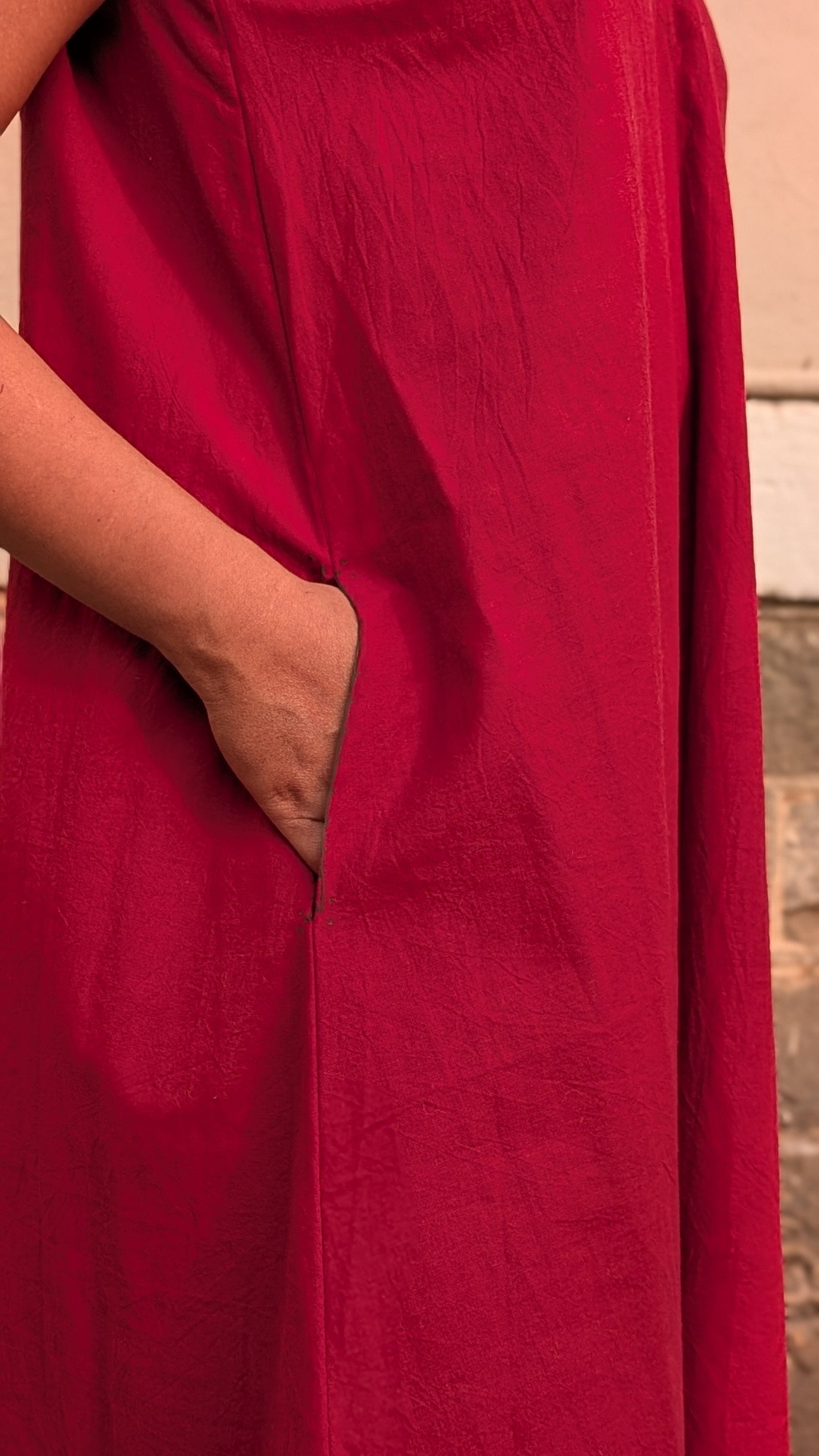 Deeta Ruby dress displayed on a hanger, showcasing its vibrant red fabric and elegant design suitable for stylish occasions.