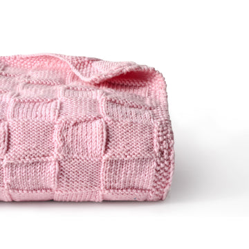 Pink Merino wool blanket by Masaya Home, soft and cozy with a plush texture, shown draped on a bed.