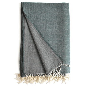 Deep teal and grey throw blanket from Bombaybirds, soft woven living room accessory displayed in petrol grey color.