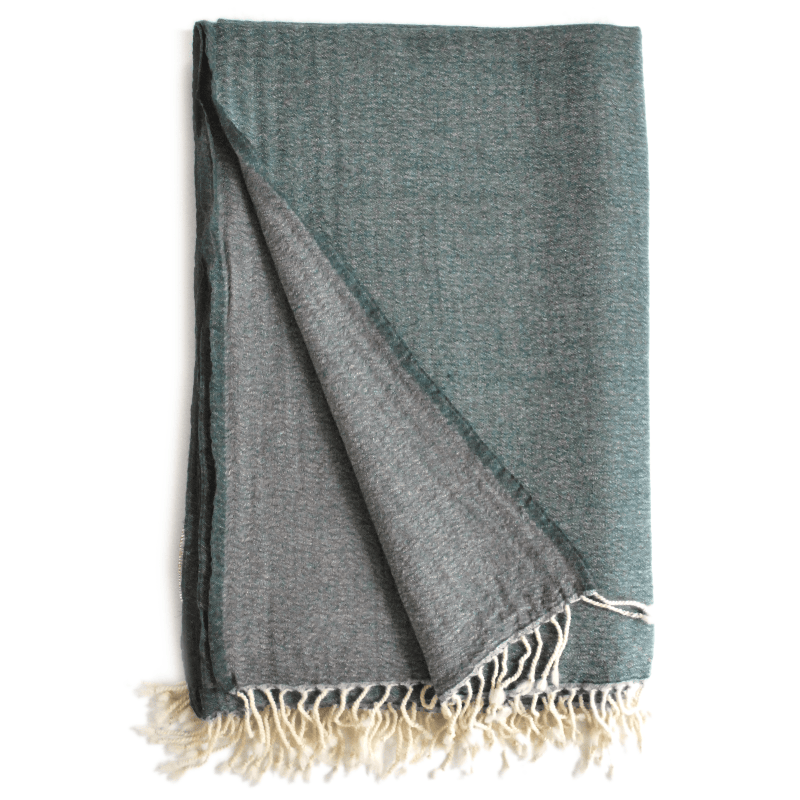 Deep teal and grey throw blanket from Bombaybirds, soft woven living room accessory displayed in petrol grey color.