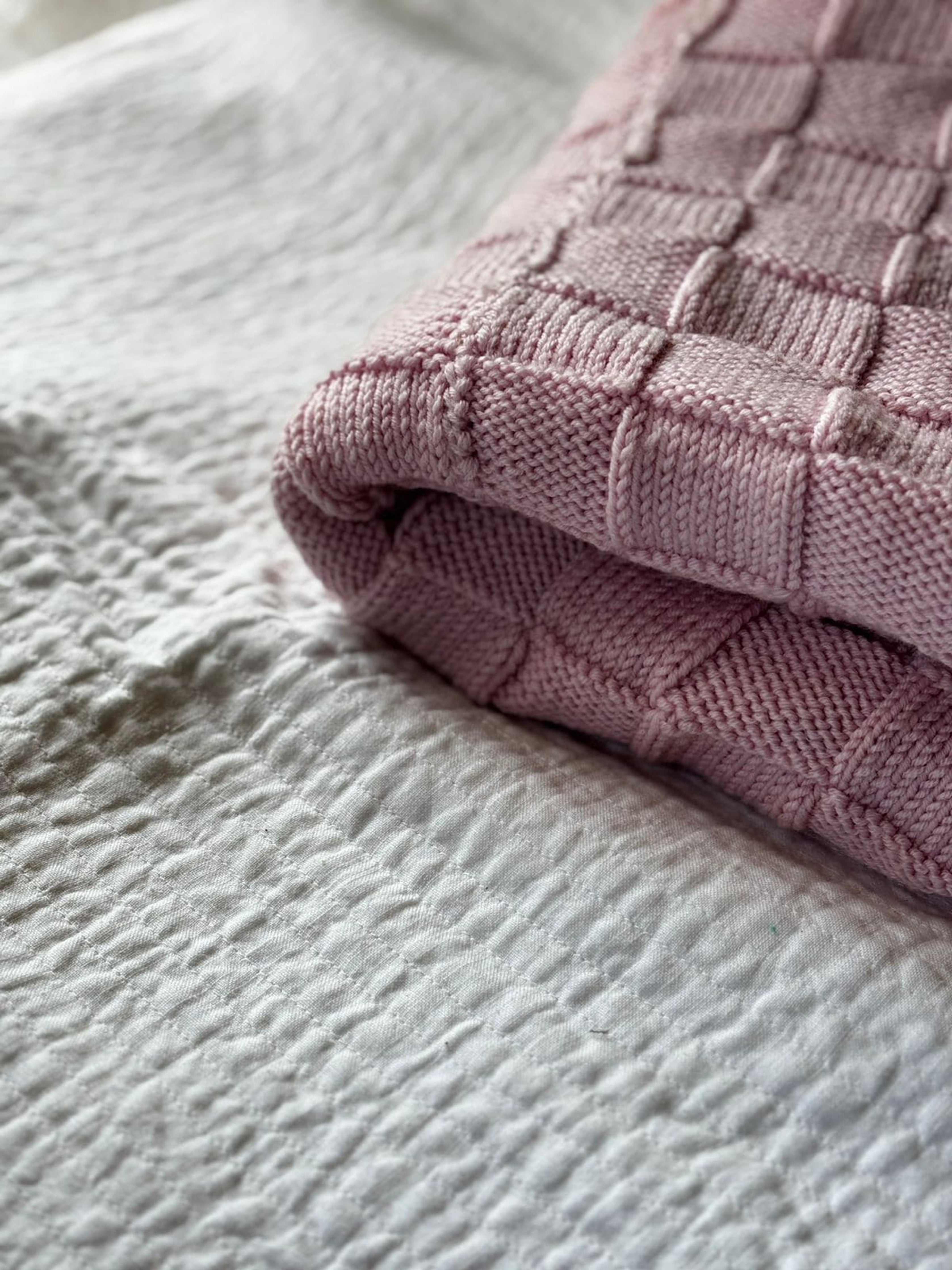 Pink Merino wool blanket by Masaya Home, soft and cozy with a plush texture, displayed folded on a neutral background.