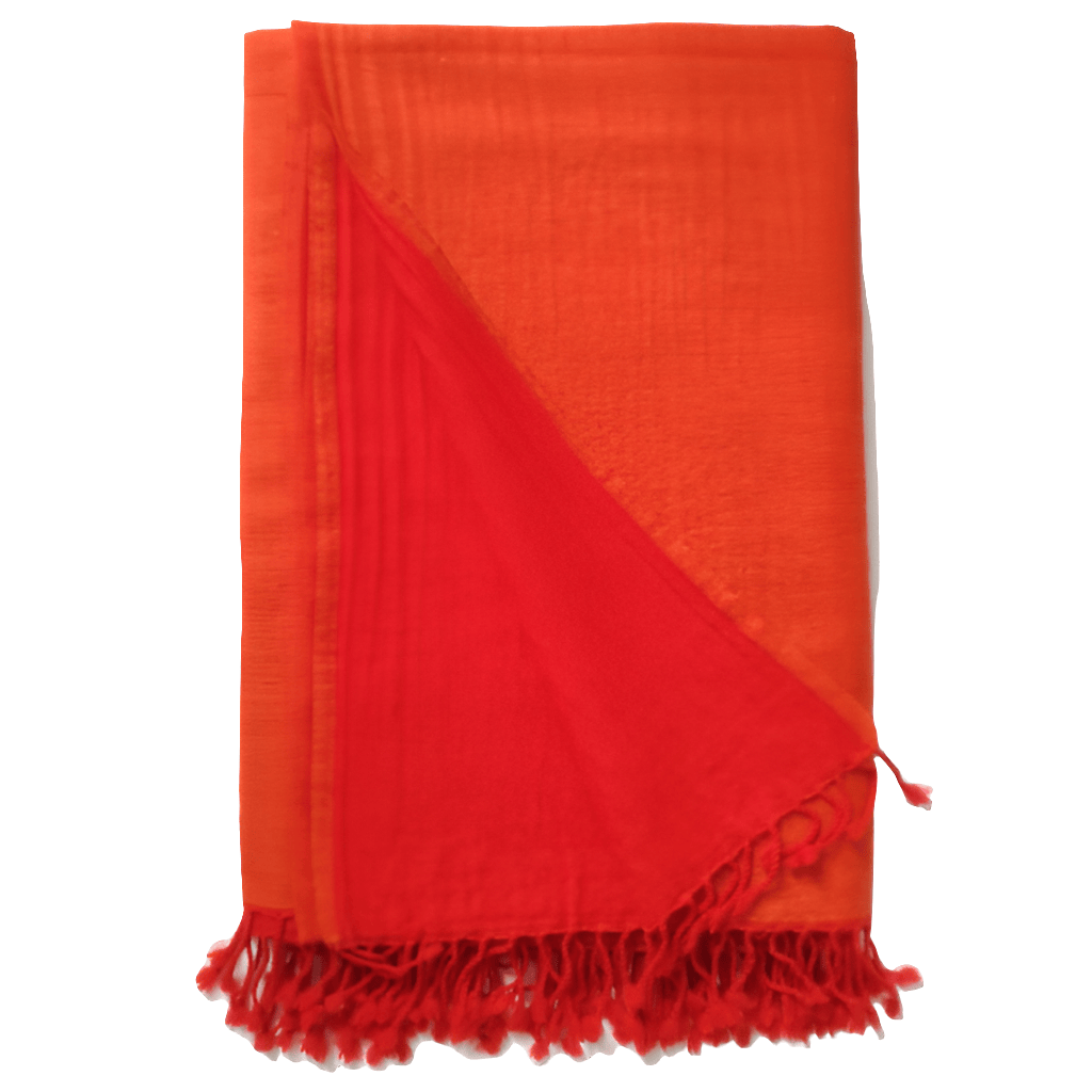 Flamed tangerine Bombaybirds living throw blanket draped over a couch, showcasing vibrant orange and fiery patterned fabric.