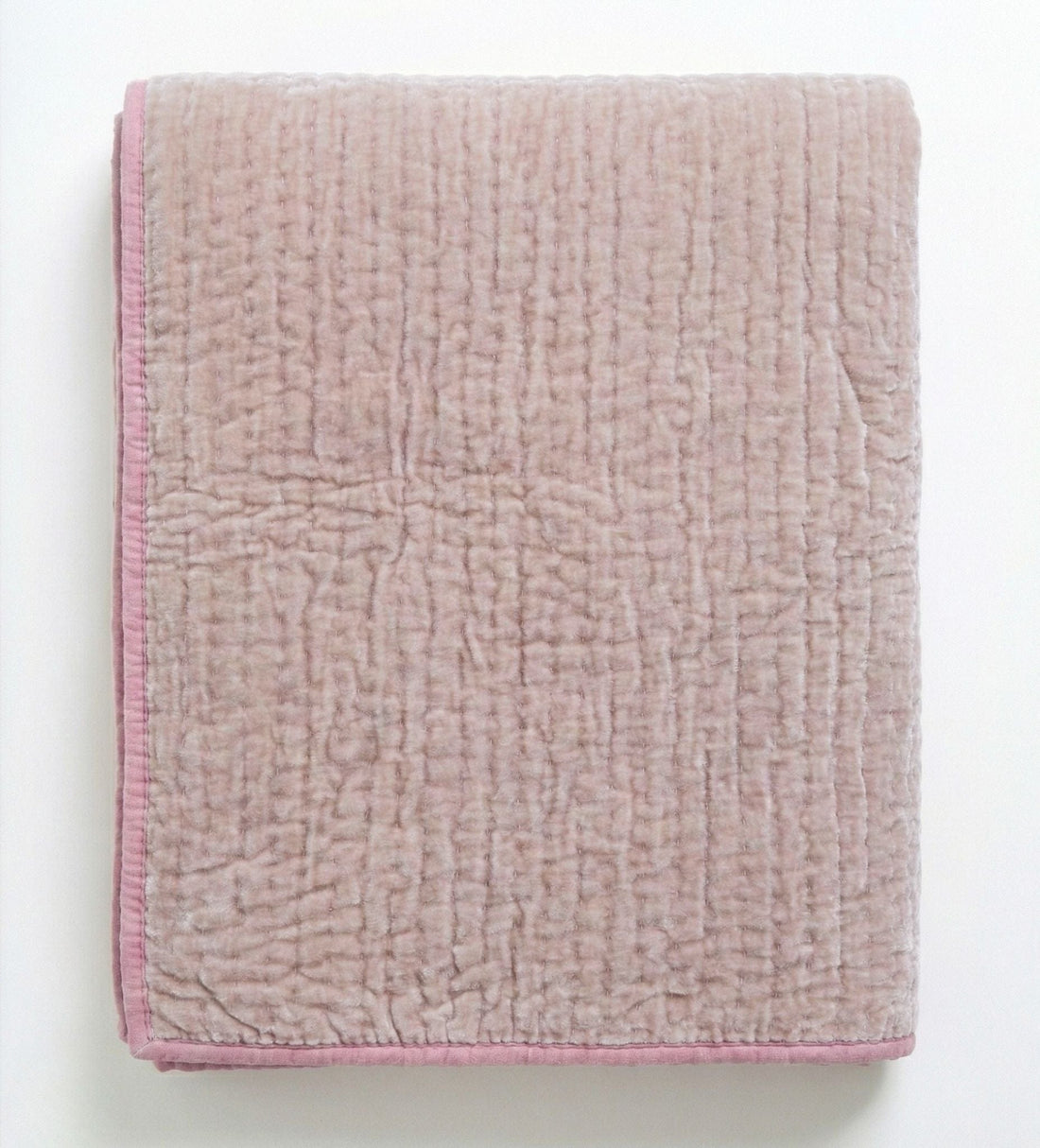 Soft blush rose velvet reversible quilt from Bombaybirds, showcasing plush, taupe-colored fabric on a cozy living room setting.
