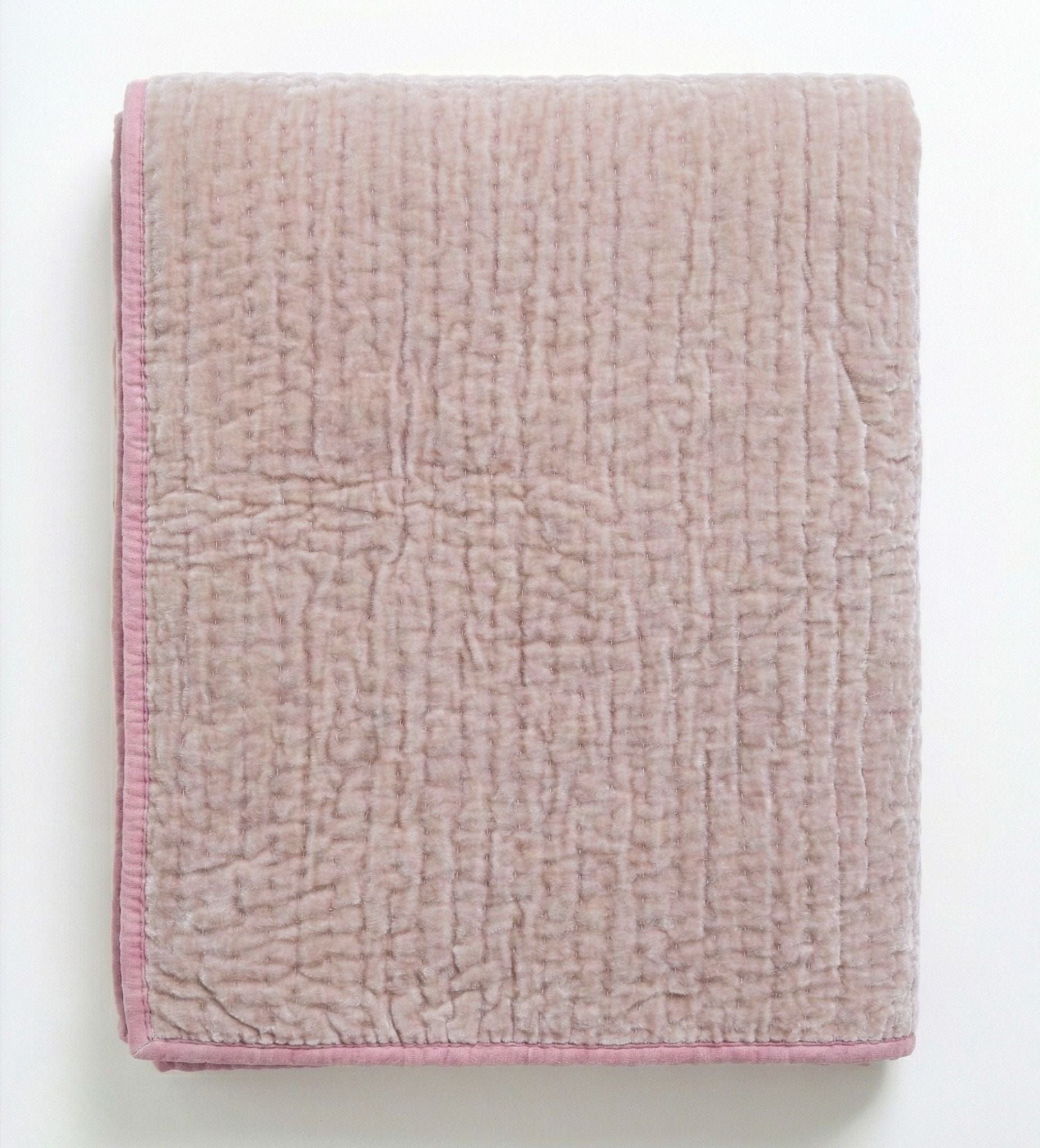 Soft blush rose velvet reversible quilt from Bombaybirds, showcasing plush, taupe-colored fabric on a cozy living room setting.