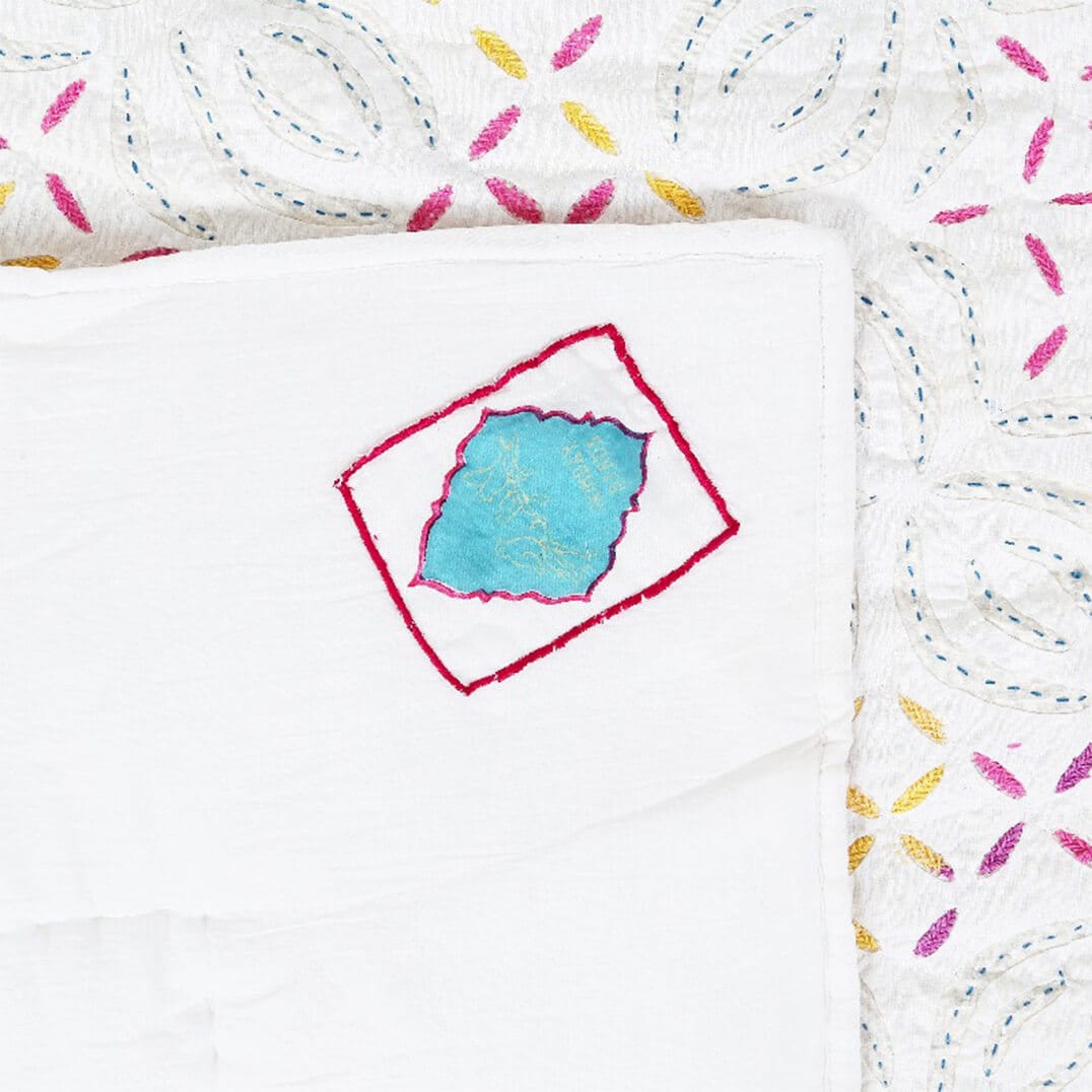 Colorful Kutch rainbow quilt by Bombaybirds, featuring vibrant traditional patterns on a living room setting.