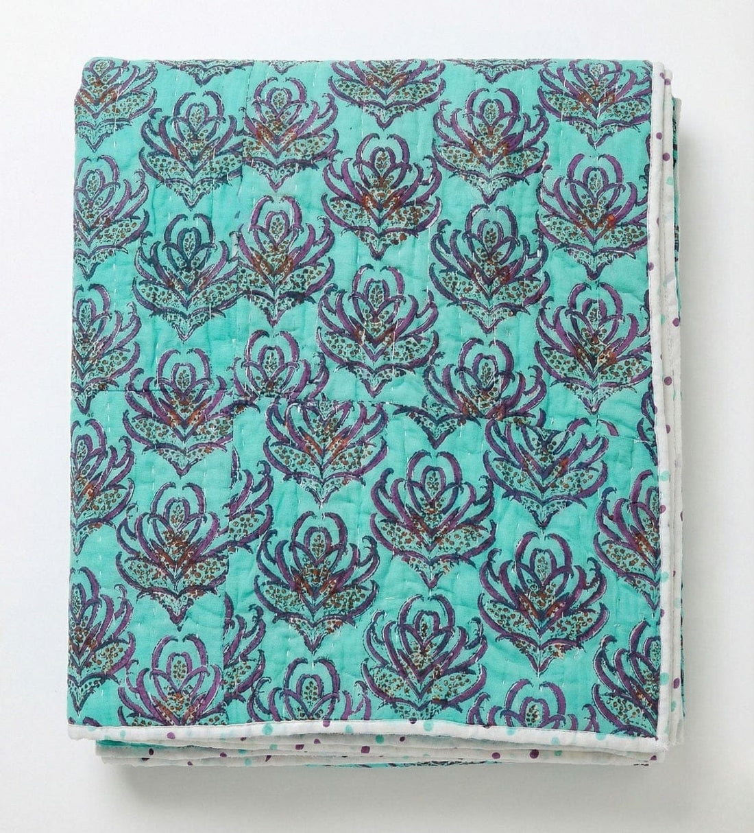 Pink lotus reversible quilt from Bombaybirds, showcasing vibrant pink and turquoise lotus blockprint fabric on a cozy living quilt.