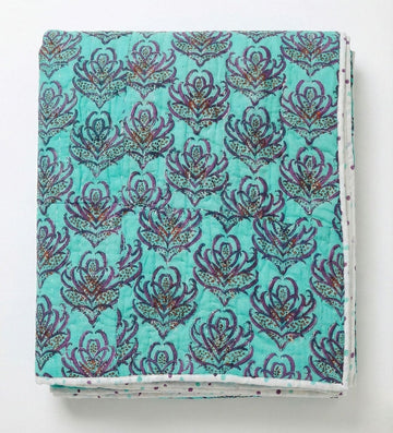 Pink lotus reversible quilt from Bombaybirds, showcasing vibrant pink and turquoise lotus blockprint fabric on a cozy living quilt.