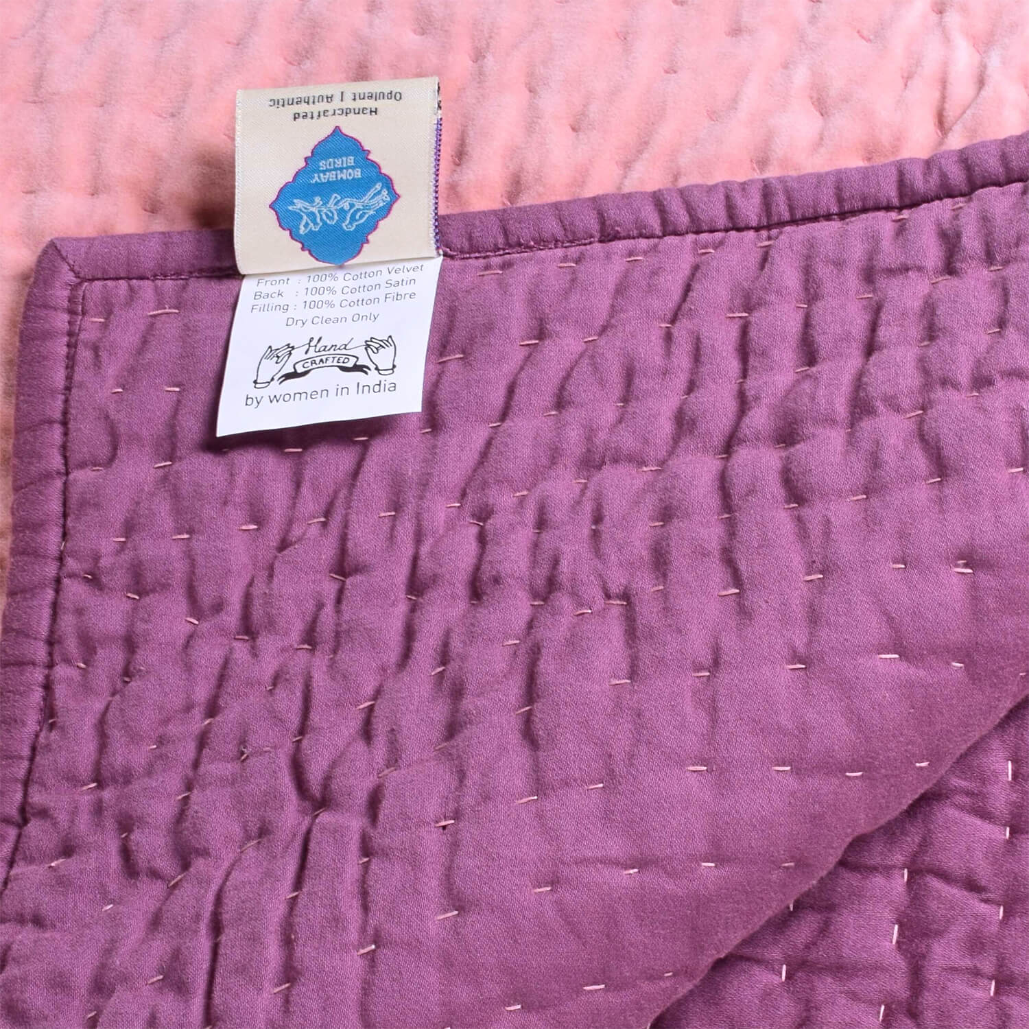 Pink velvet reversible quilt from Bombaybirds with a soft, plush texture and intricate stitching, perfect for cozy living room decor.