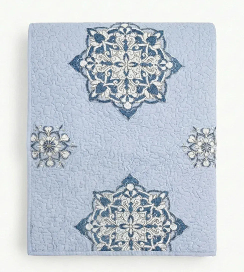 Light blue lilac Suzani quilt from Bombaybirds, shown as a decorative living room throw with intricate floral patterns.