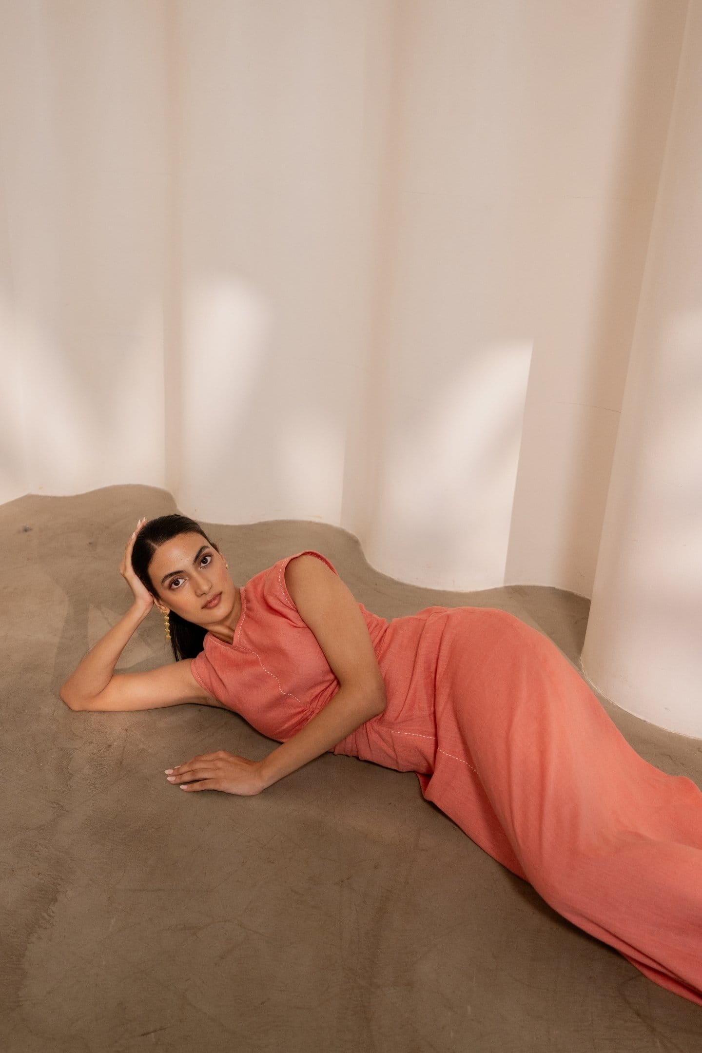 Orange Dawn cinched maxi dress by Alternative, featuring a fitted waist and flowing fabric, displayed on a hanger.