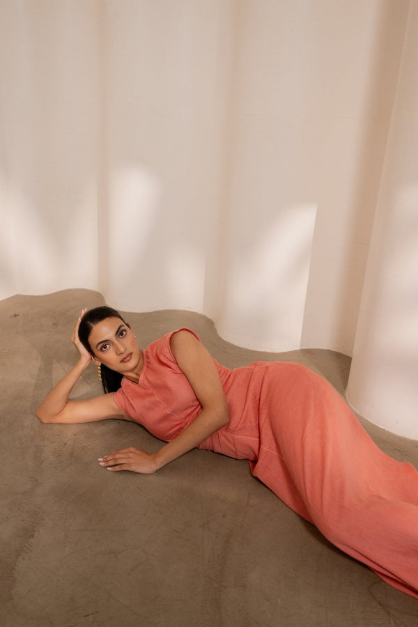Orange Dawn cinched maxi dress by Alternative, featuring a fitted waist and flowing fabric, displayed on a hanger.