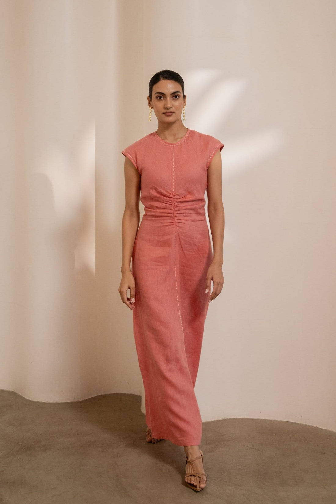 Orange Dawn cinched maxi dress by Alternative, featuring a fitted waist and flowing fabric, displayed on a hanger.