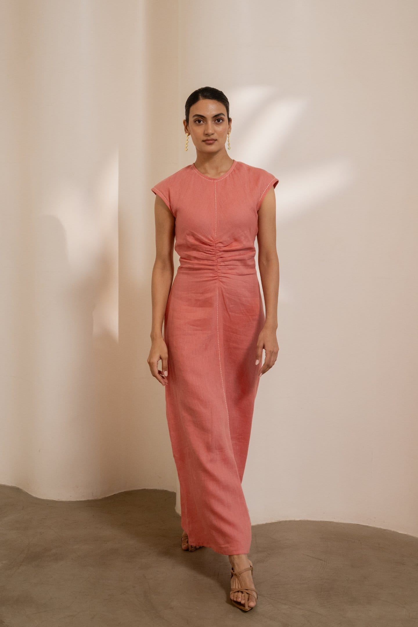 Orange Dawn cinched maxi dress by Alternative with gathered waist and flowing fabric, displayed on a hanger.