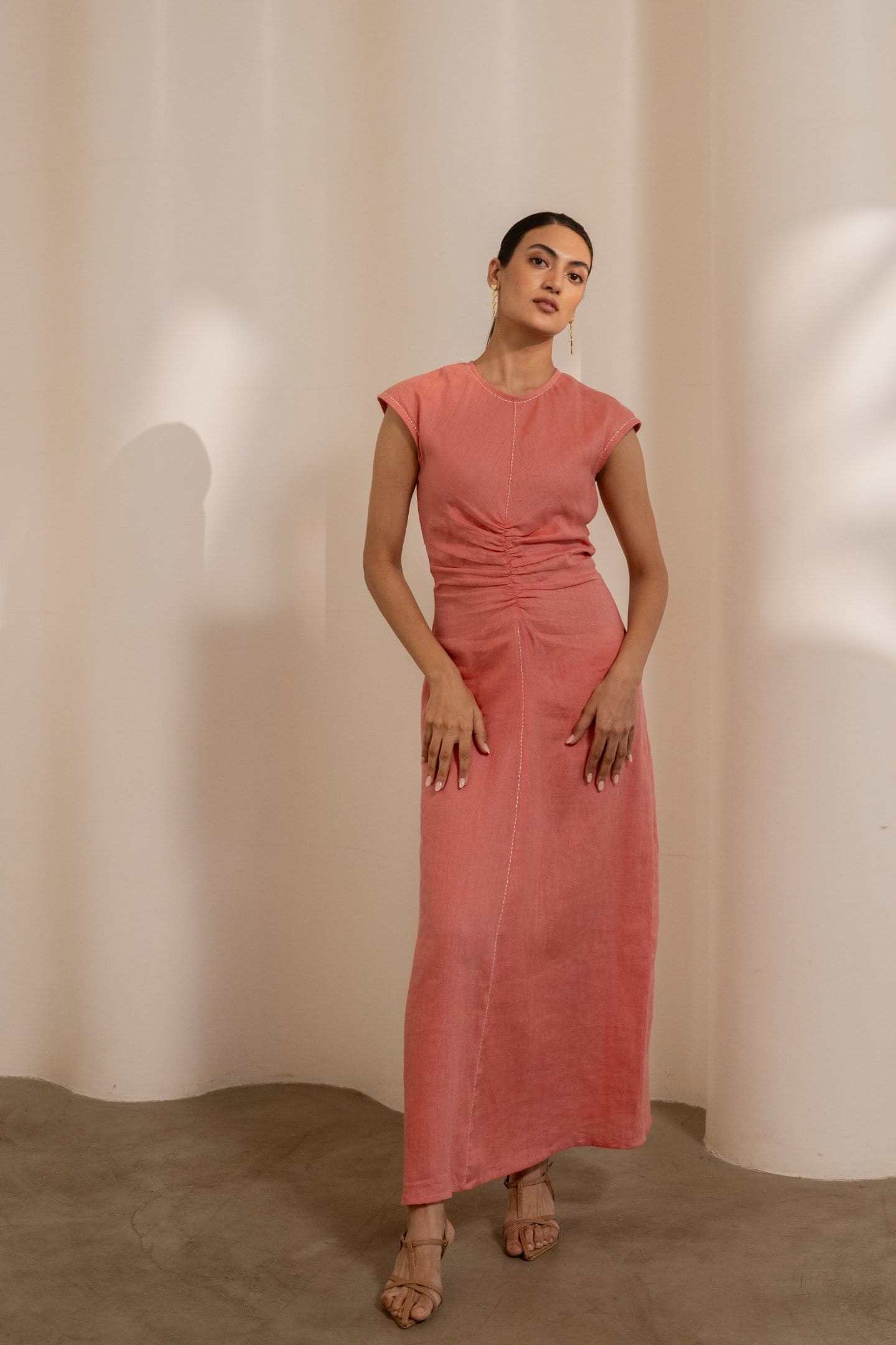 Orange Dawn cinched maxi dress by Alternative, featuring a fitted waist and flowing fabric, displayed on a model.