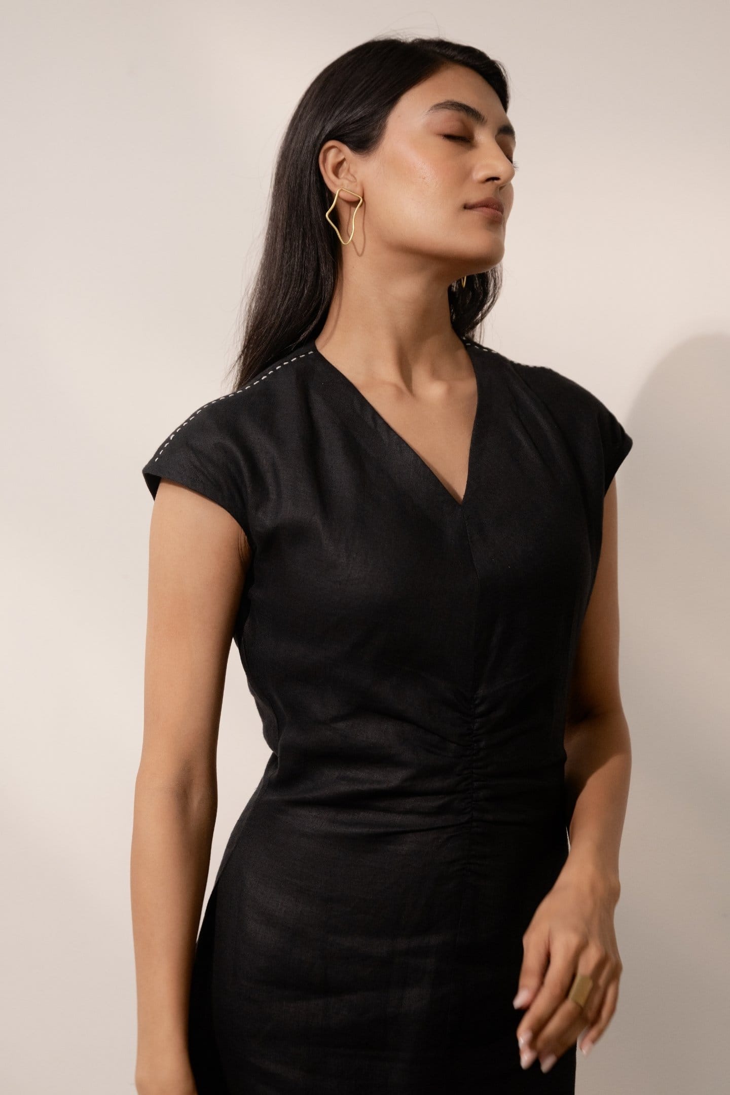 Ebony black cinched maxi dress by Alternative, featuring a fitted waist and flowing fabric, displayed on a hanger.
