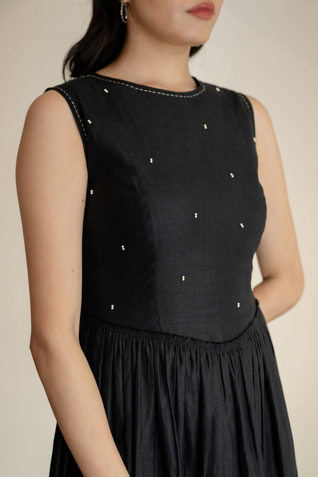 Ebony black sleeveless maxi dress by Alternative, flowing midi length with a fitted waist and elegant round neckline.