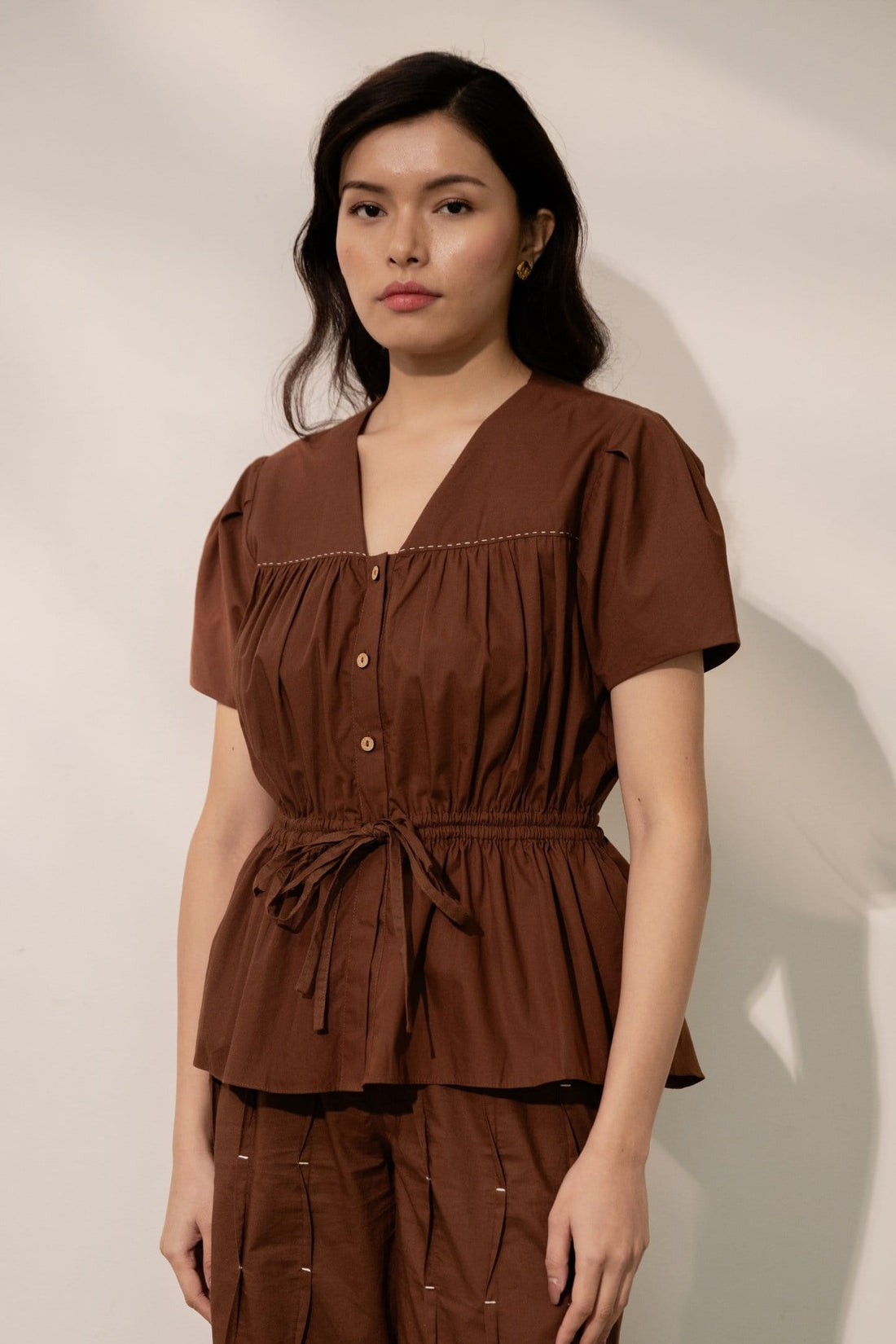Alternative Ether brown tie-up top with long sleeves and V-neck, featuring a stylish front tie detail.