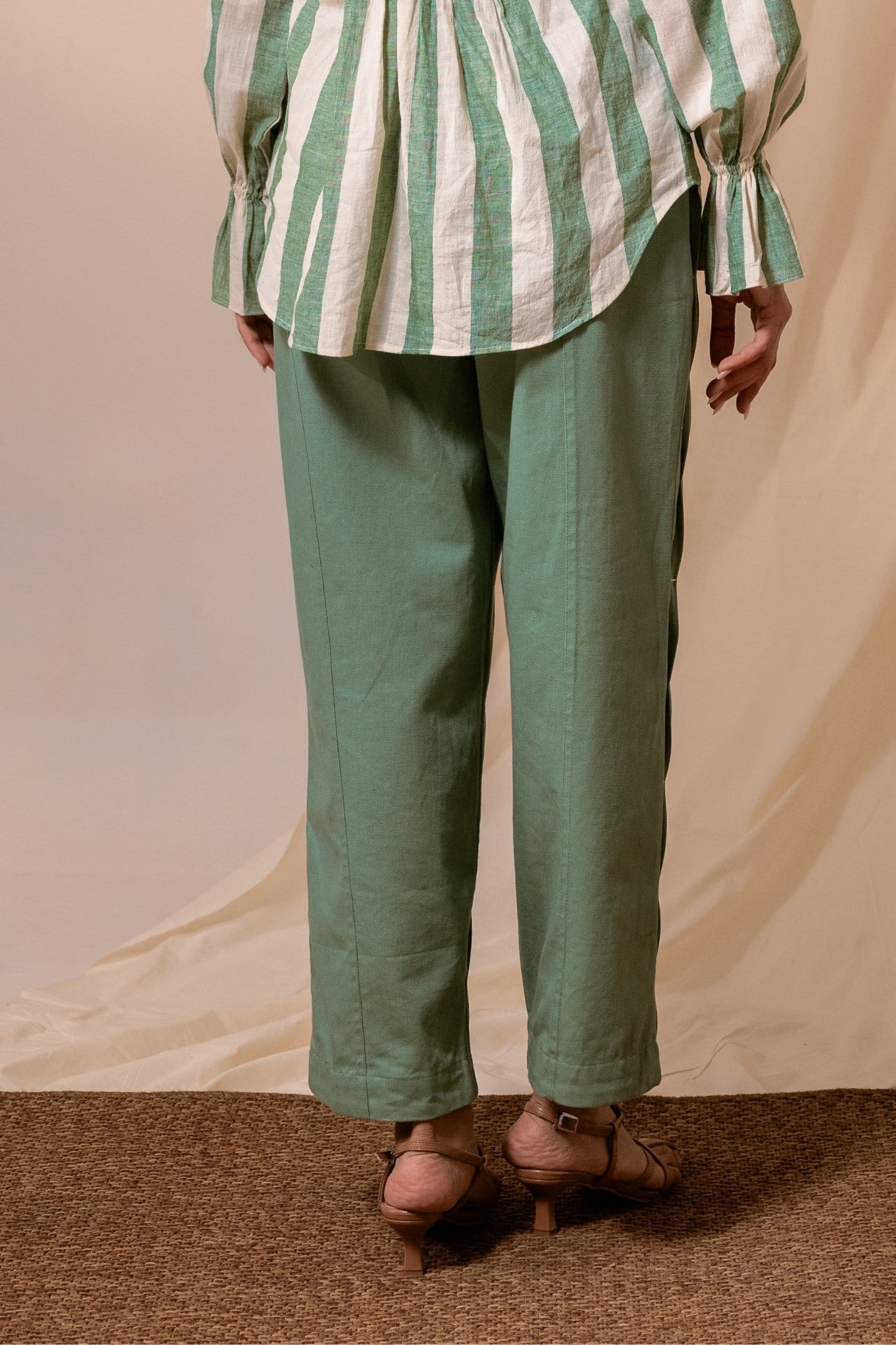 Fern green denim pleated trousers by Alternative, showcasing the relaxed fit and stylish pleats in a close-up shot.