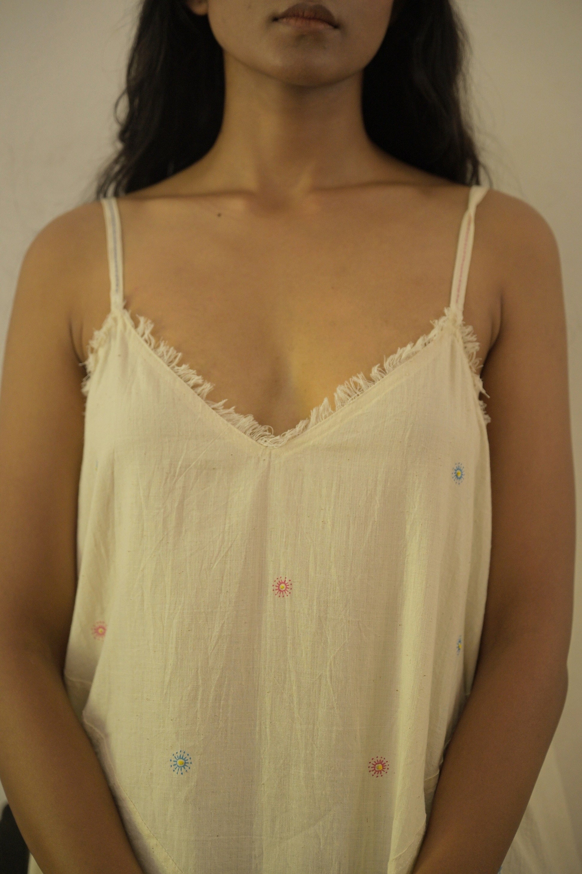 Deeta Hana slip dress displayed on a hanger, showcasing its sleek, lightweight fabric and simple, elegant design.