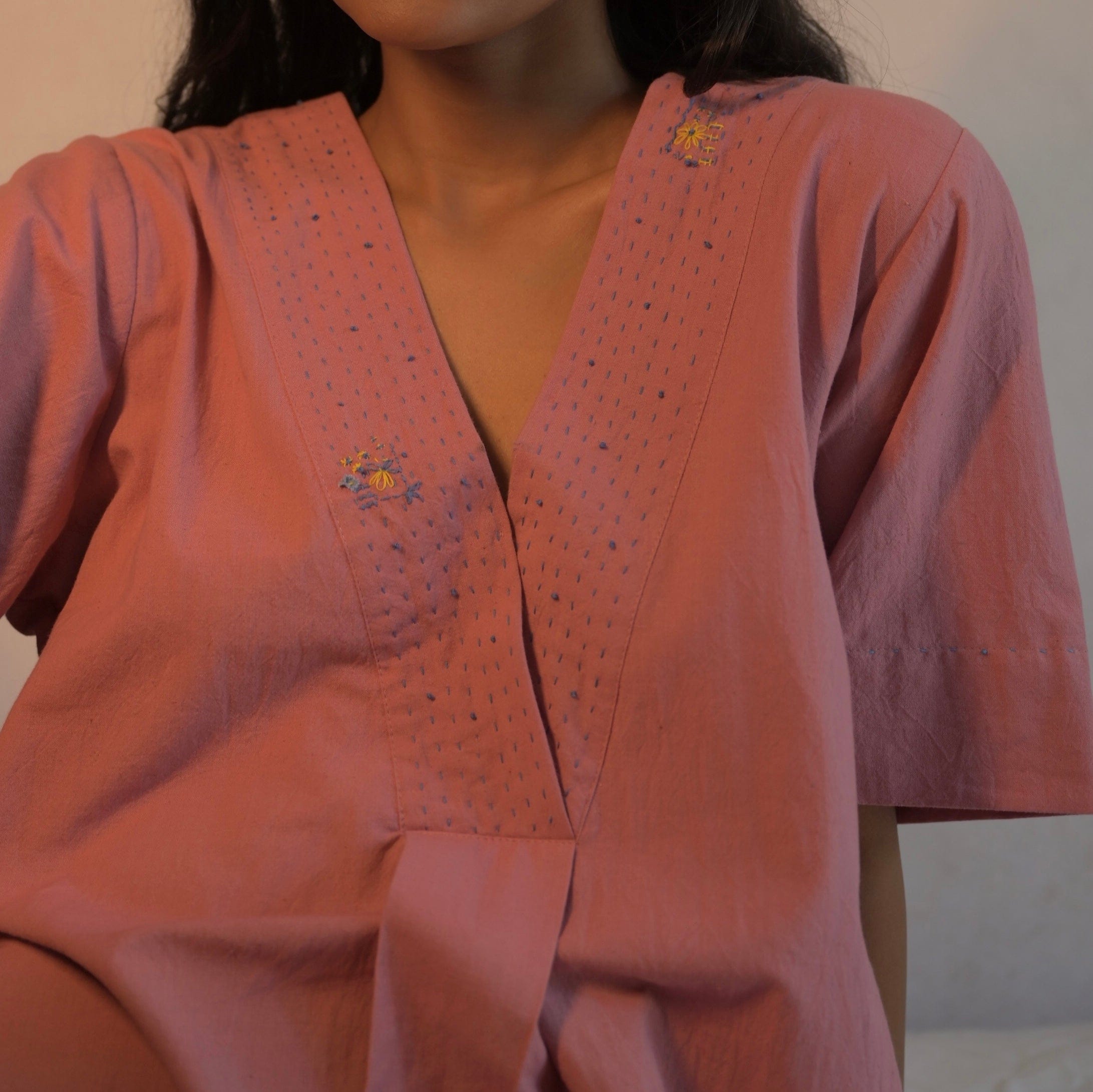 Deeta Rosa dress displayed on a hanger, showcasing a stylish pink dress with floral details and elegant design.