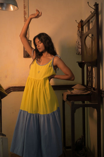 Deeta Kira slip dress featuring a smooth fabric and elegant design, displayed on a hanger with a blurred background.