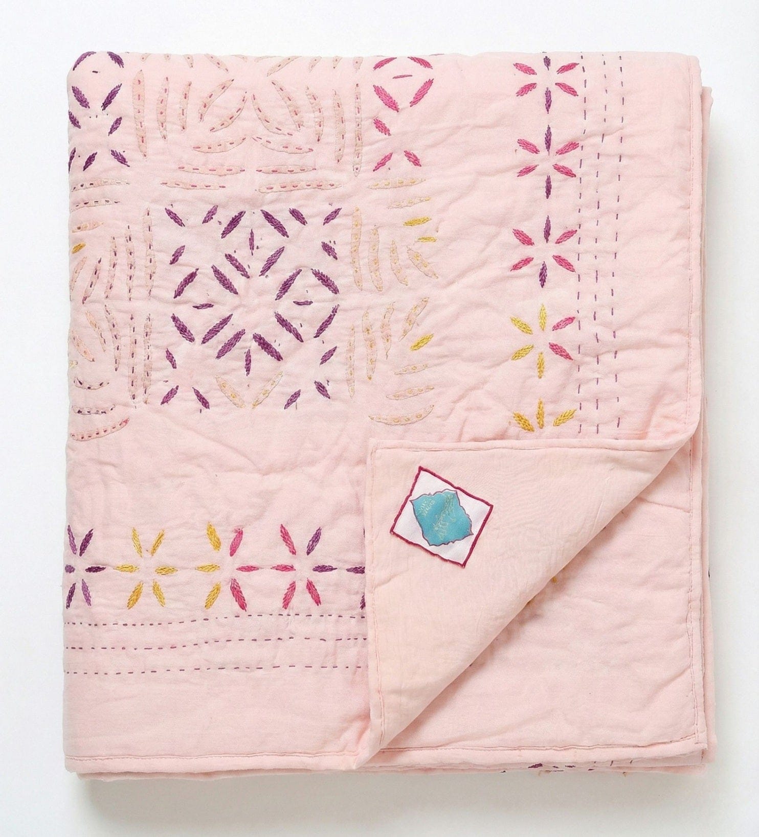 Handcrafted blush quilt applique from Bombaybirds, showcasing intricate stitching and textured fabric in apricot and peach tones.