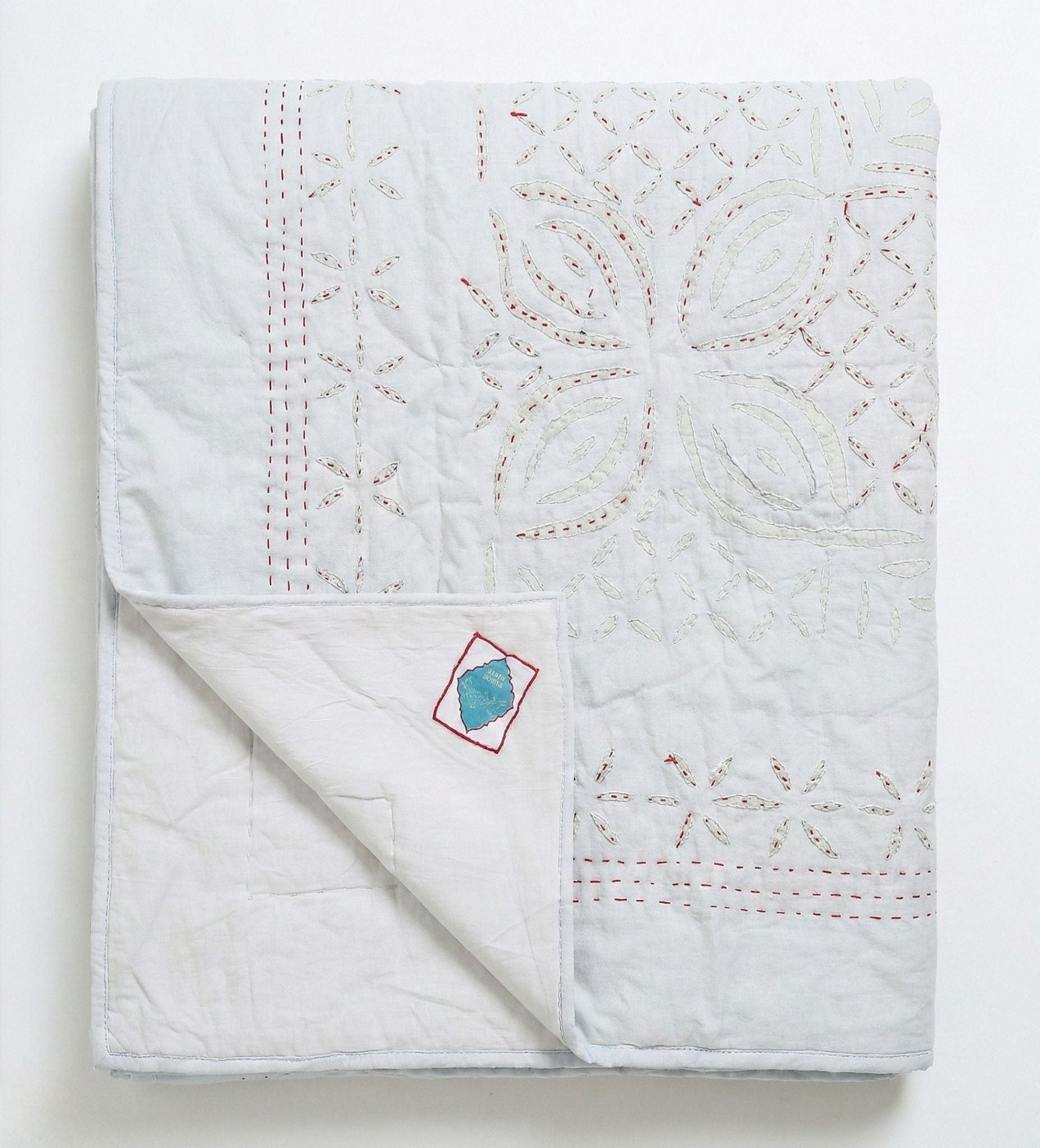 Bombaybirds sky quilt applique for living room, hand-stitched light blue cotton with delicate floral embroidery.