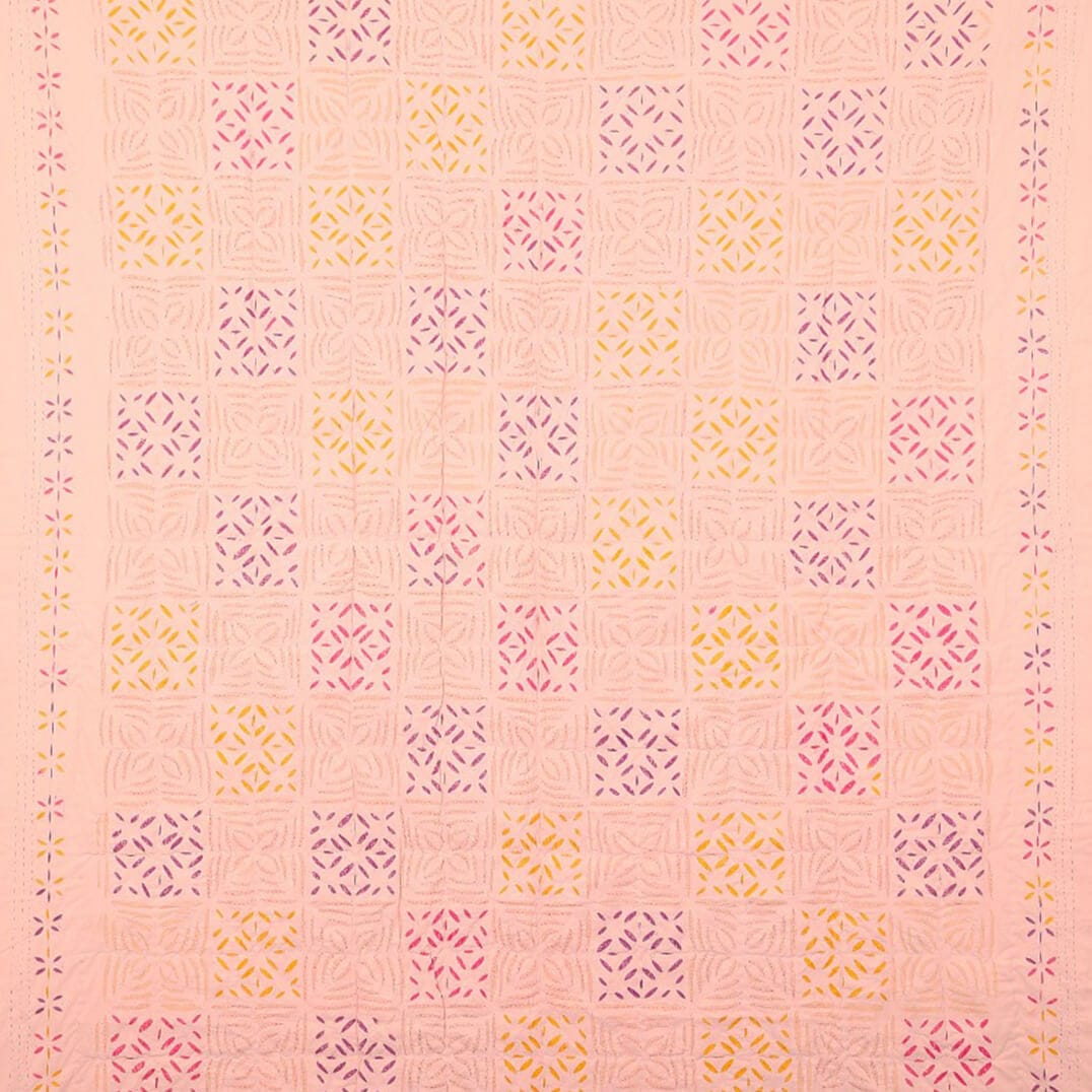 Applique blush quilt with geometric pattern, apricot and peach tones, designed for living room decor by Bombaybirds.