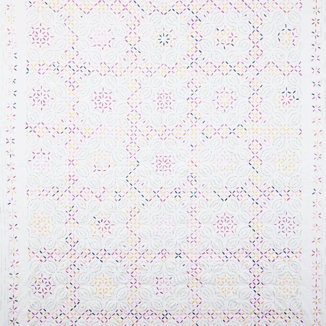 Colorful Kutch rainbow quilt from Bombaybirds with geometric patterns, perfect for a living room decor.
