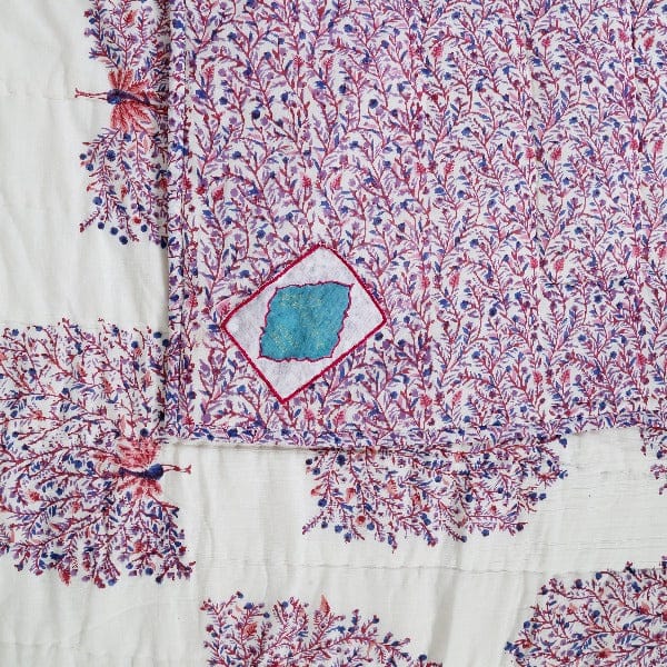 Reversible quilt with peacock feather design by Bombaybirds, showcasing luxurious colorful feathers on a cozy bedding.