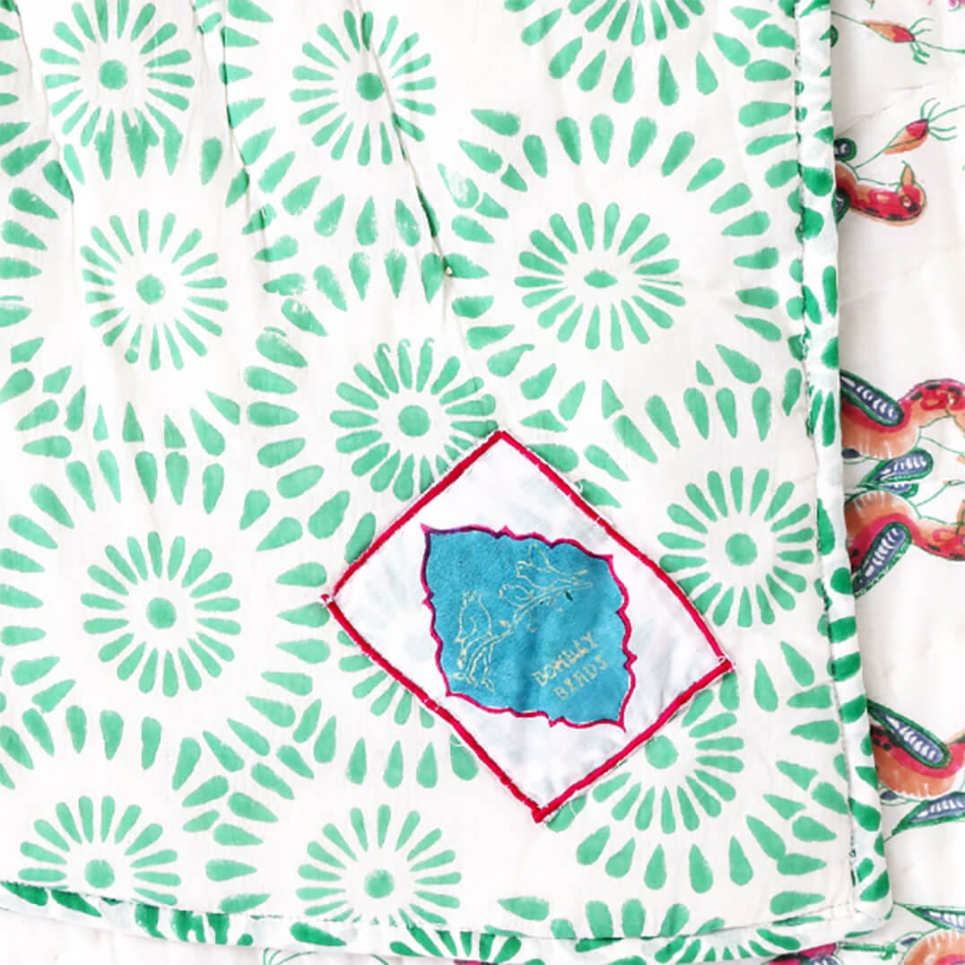 Reversible Ornitho blanket by Bombaybirds featuring green and white block print design, traditional living room decor.