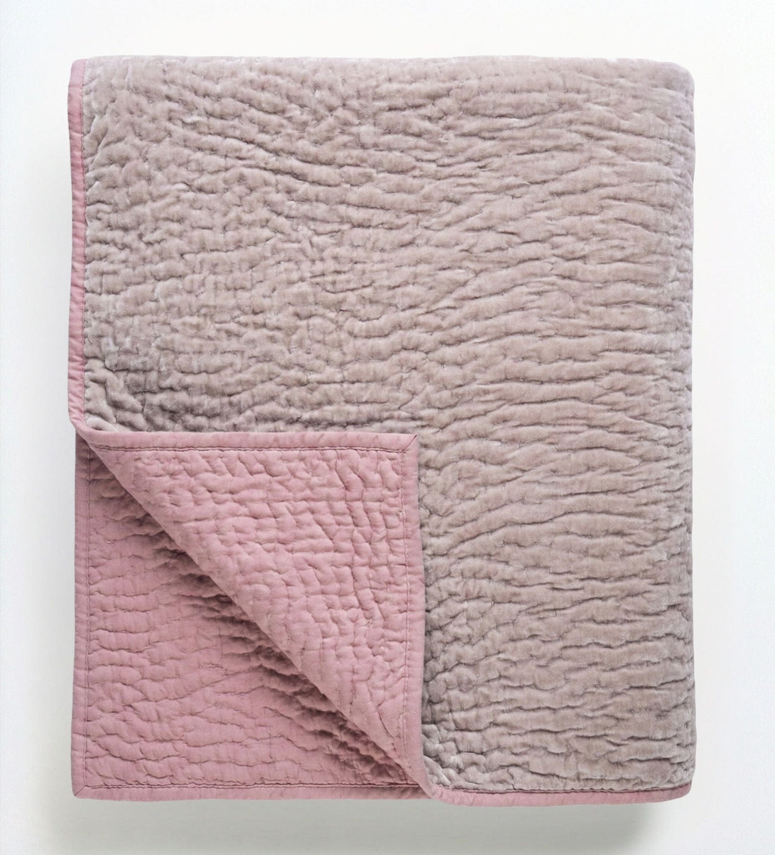 Soft blush rose velvet reversible quilt from Bombaybirds, showcasing plush, taupe-colored fabric on a cozy living room setting.