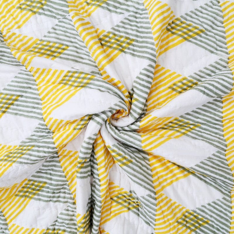 Close-up of Bombaybirds Sunnie chintz reversible quilt in soft cotton with textured, floral pattern for living room decor.
